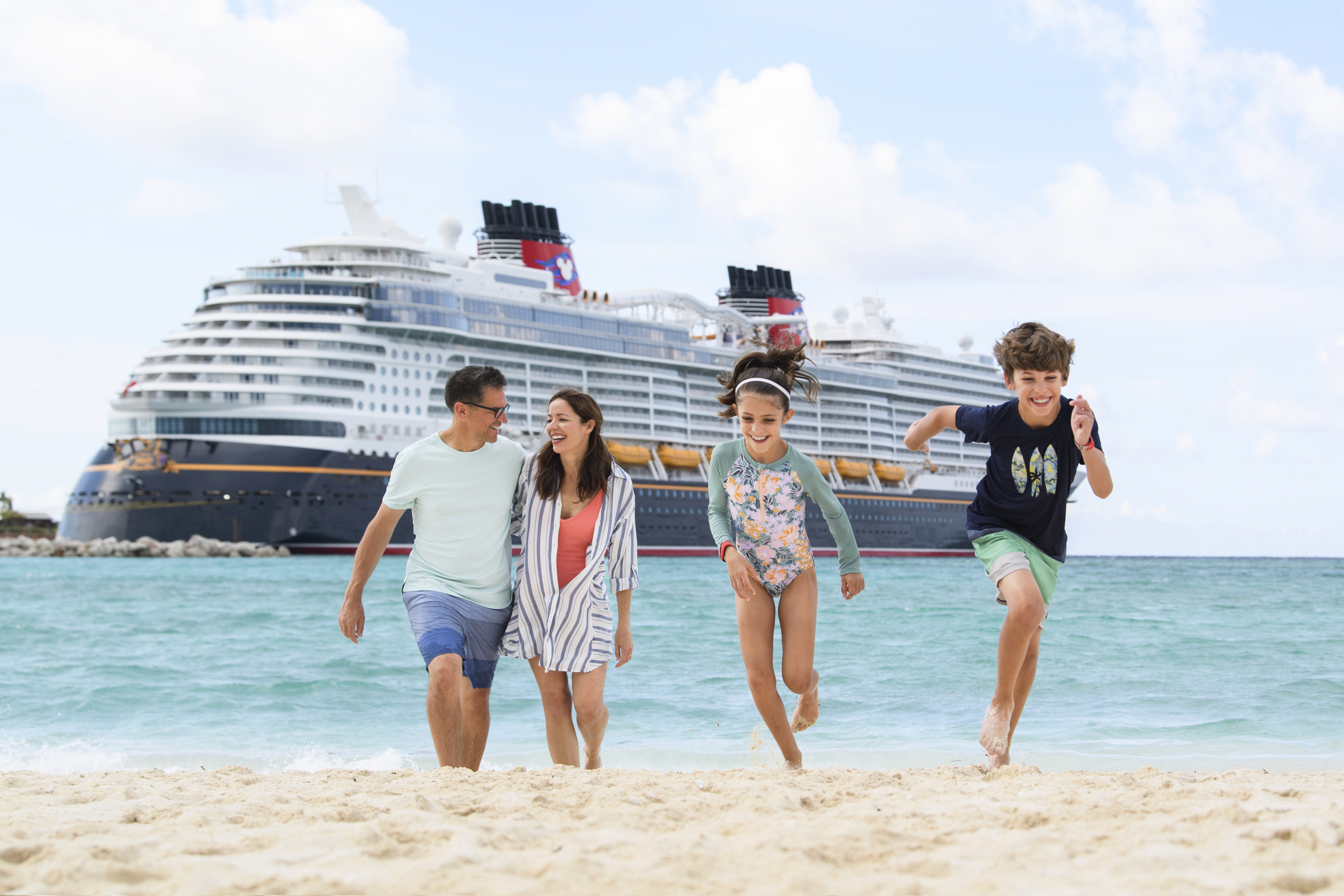 Happy family on beach with Disney cruise ship - Disney Cruise Line travel agent Utah